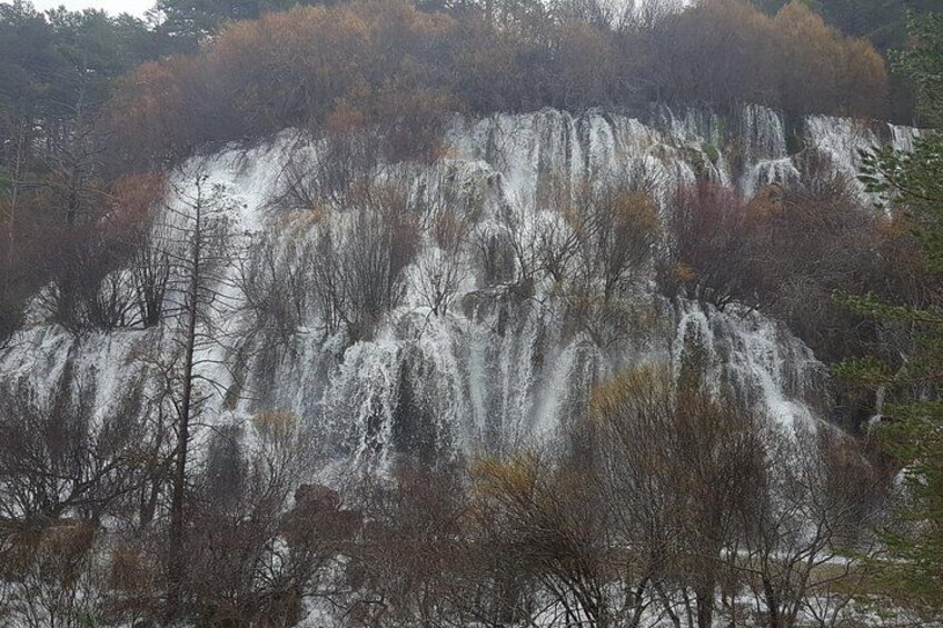 Une cascade se déversant le long d’une falaise rocheuse, entourée d’arbres. 1