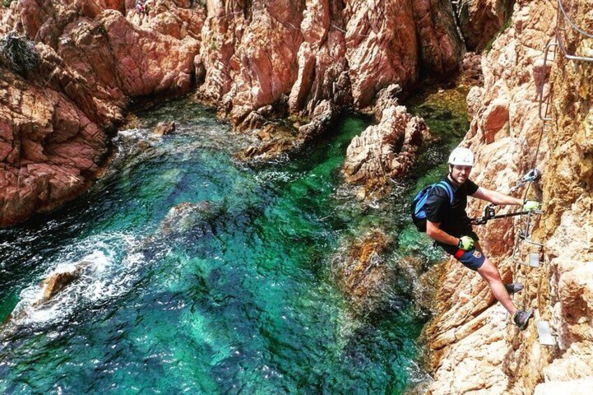 A person rappelling down a rocky cliff with a river below. 2