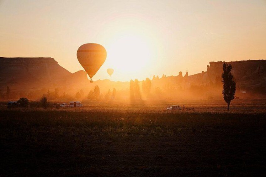 A hot air balloon in a field with mountains in the background. 2