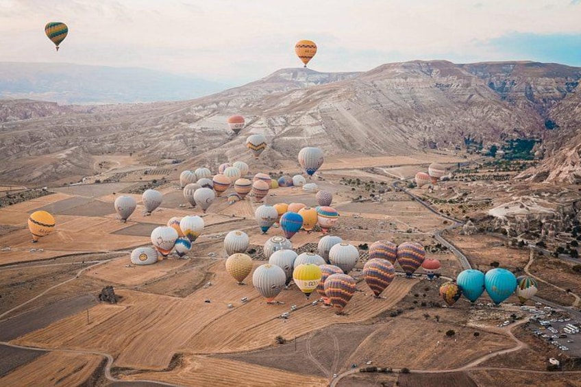 A hot air balloon festival with numerous balloons in various colors over a rugged landscape. 5