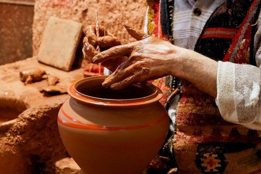 Hands shaping a clay pot on a pottery wheel. 2