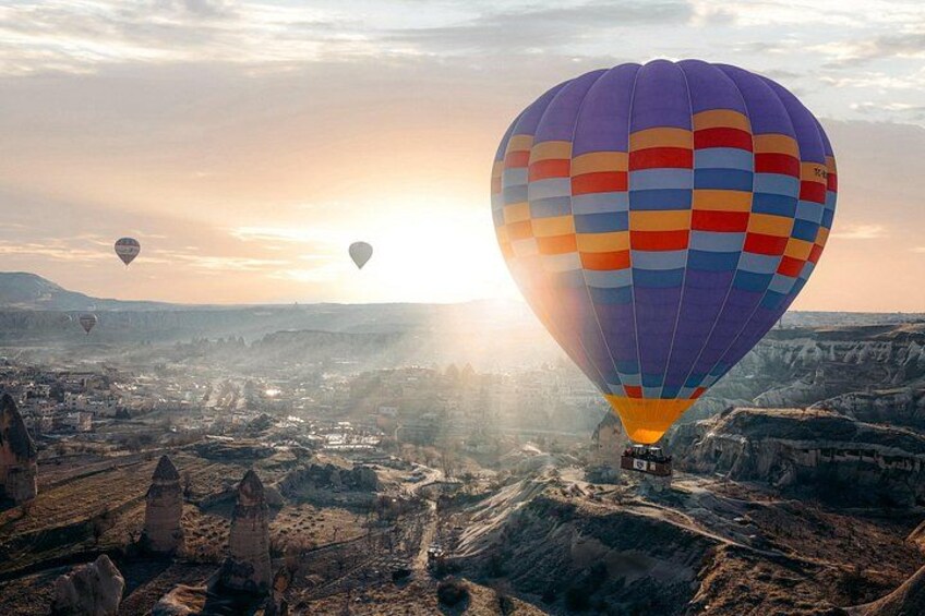 A hot air balloon over a rugged landscape with multiple balloons in the distance. 3