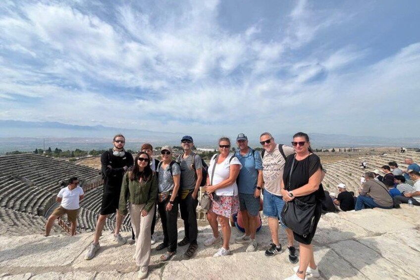 A group of people standing on an ancient amphitheater with a clear sky in the background. 3