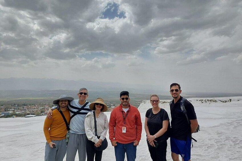 A group of people standing on a snowy mountain with a cloudy sky in the background. 2