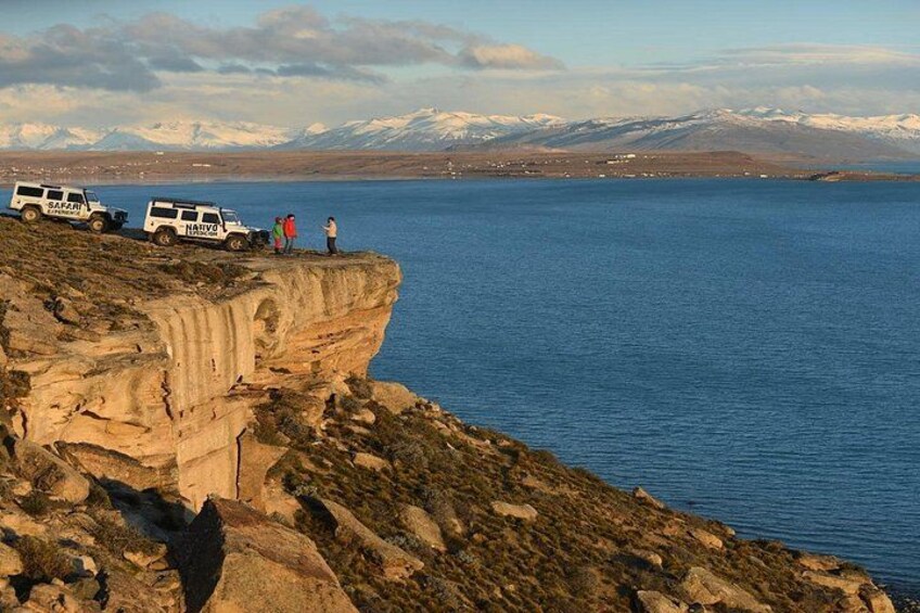 A cliff overlooking a body of water with a mountainous background. 1