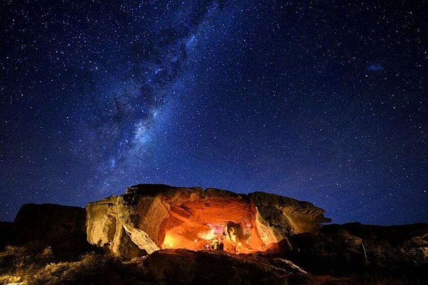 A starry night sky with a cave illuminated by fire. 2