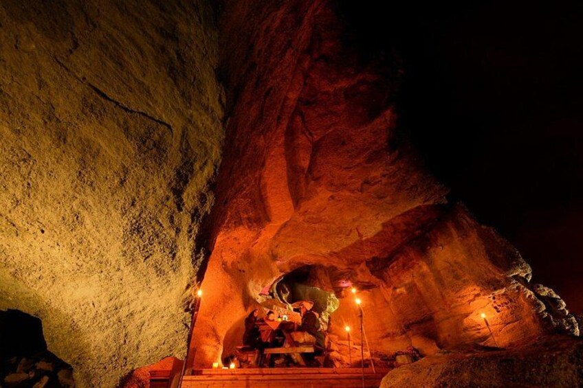 A cave interior with a large rock formation and a small shrine with candles. 3