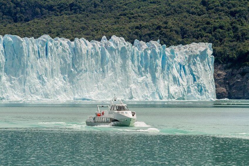 A boat on calm water with a large glacier in the background. 2
