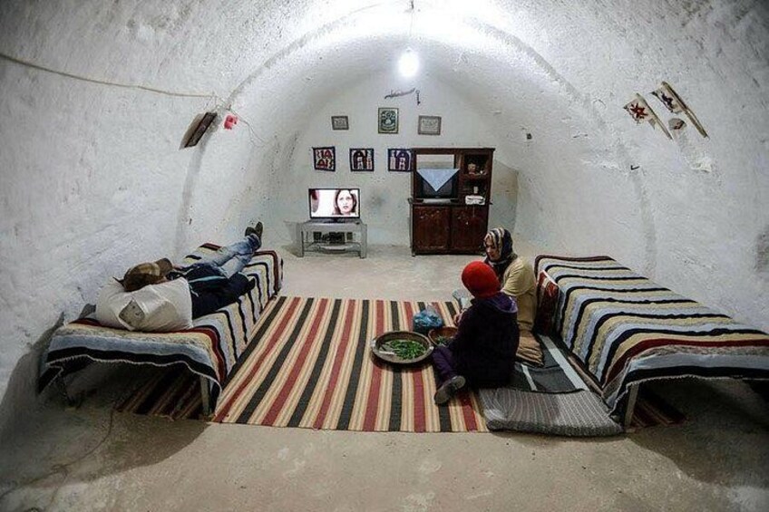A small, enclosed room with two beds, a television, and a few framed pictures on the wall. 3