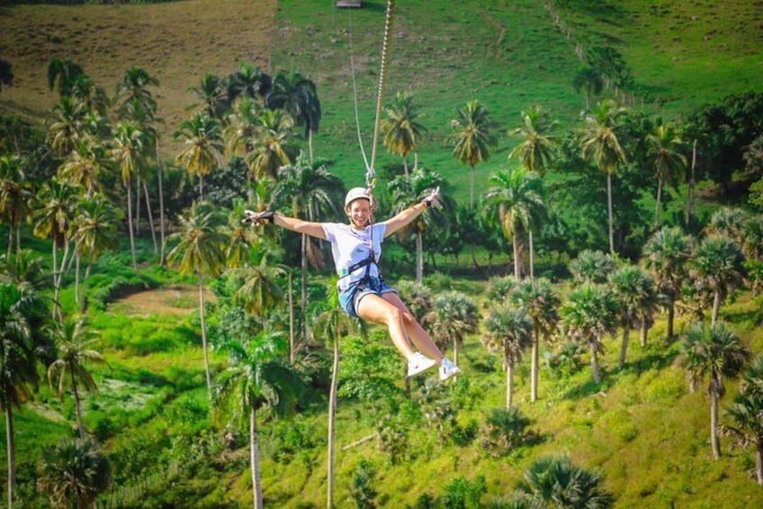 A person swinging on a rope swing over a lush green landscape with palm trees. 4