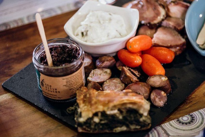 A charcuterie board with meats, olives, and a jar of sauce. 2