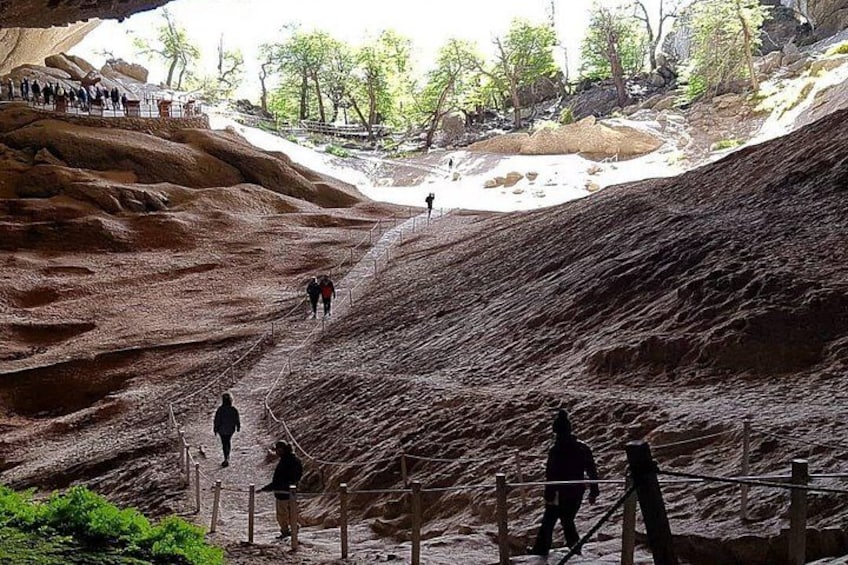 Un sendero rocoso con gente caminando, una zona cercada y árboles al fondo. 3