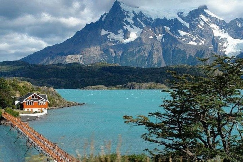 Una casa frente a un lago turquesa con una montaña al fondo. 1