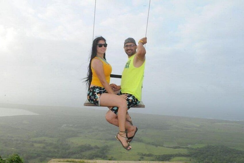 Two people on a swing suspended over a landscape. 2