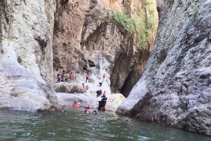 A group of people kayaking in a narrow canyon with steep rock walls. 2