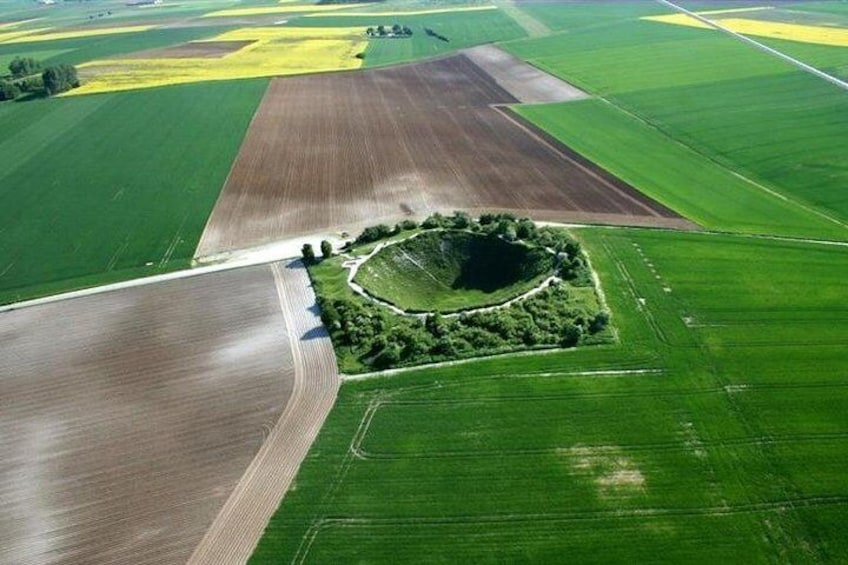 An aerial view of a large agricultural field with distinct sections of green crops and brown soil. 1