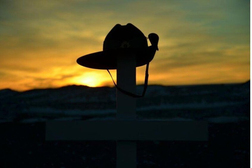 Un atardecer con la silueta de un sombrero de vaquero sobre una cruz. 1