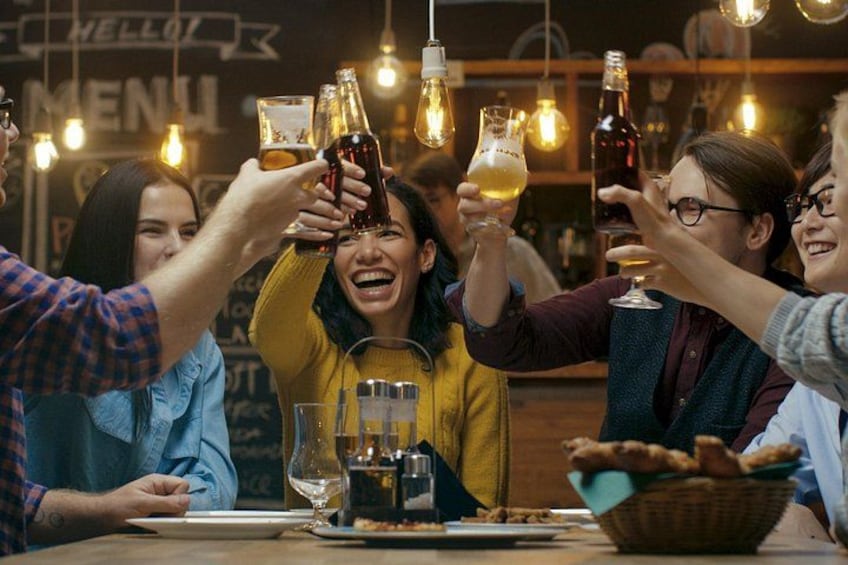 A group of people toasting with drinks at a bar. 4