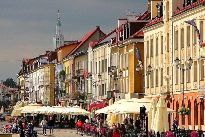 A bustling outdoor market with colorful buildings and people walking. 1