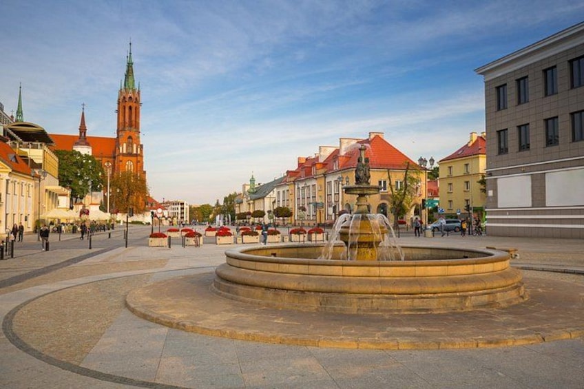 A public square with a central fountain, historic buildings, and a church in the background. 5