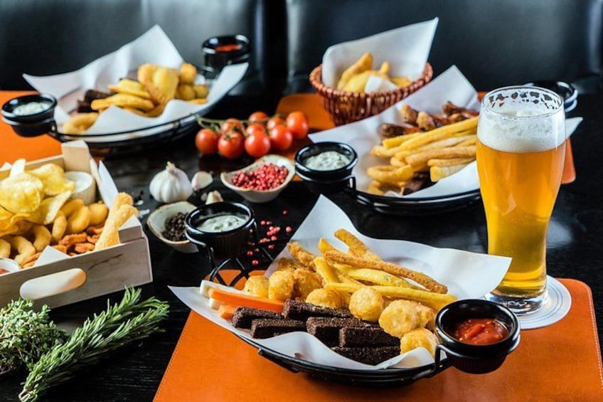 A table with various fried foods, a glass of beer, and condiments. 4