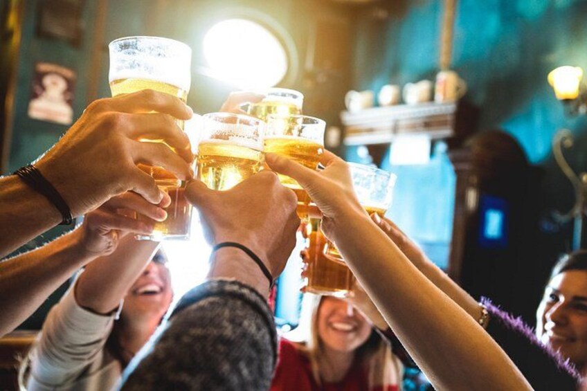 A group of people toasting with beer glasses in a bar setting. 5
