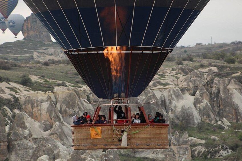 A hot air balloon with passengers above a rocky landscape. 5