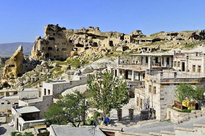 A historic town with ancient rock-cut architecture, a prominent rock formation, and a clear blue sky. 3