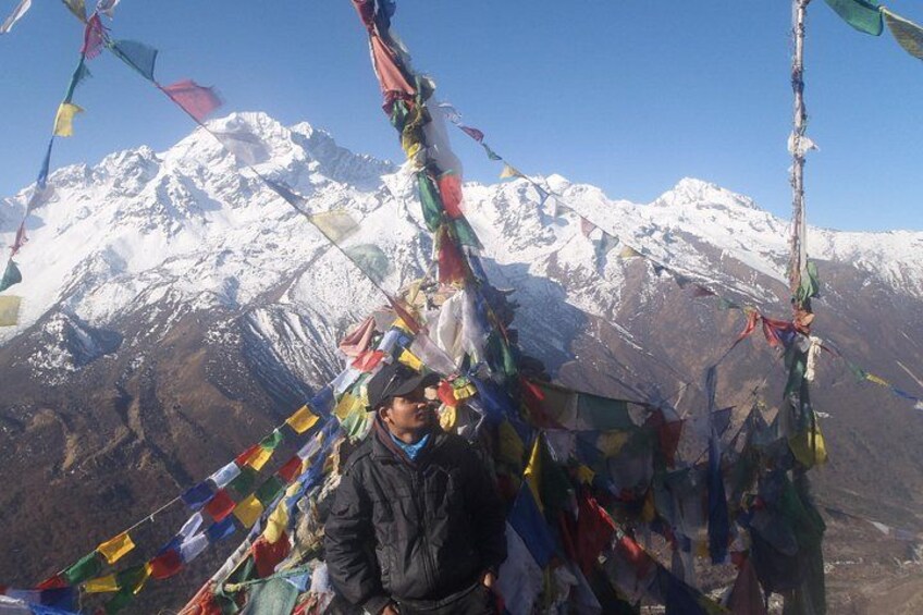 A person with colorful prayer flags in front of a snow-capped mountain. 1
