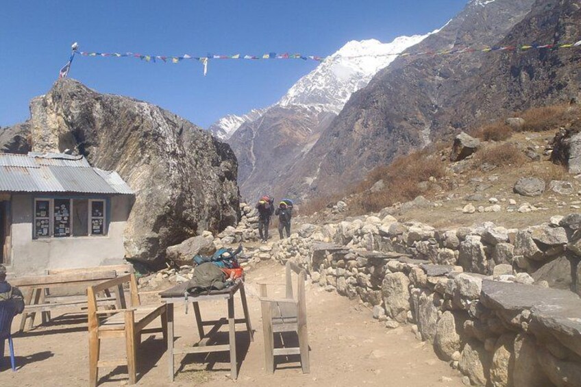 A mountainous landscape with a stone structure and a small building, likely a rest stop for hikers. 5