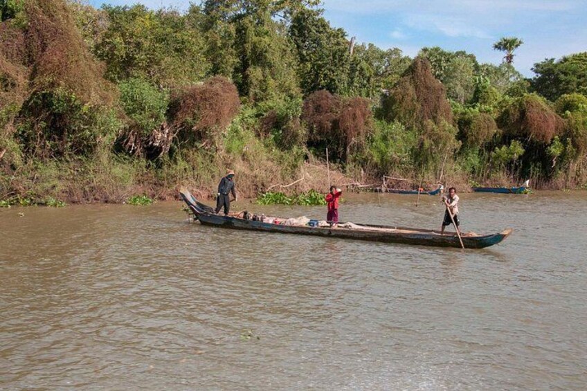 Un río con una larga embarcación de madera transportando personas. 5