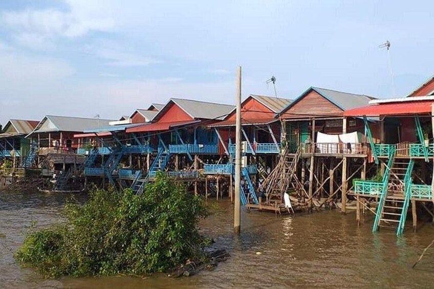 Casas flotantes con techos rojos y escaleras azules sobre el agua. 2