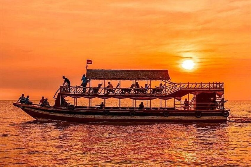 Un bote con gente a bordo, un atardecer al fondo y agua tranquila. 1