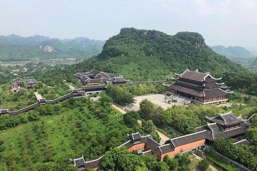 A traditional Chinese architectural complex with multiple buildings, surrounded by lush greenery and hills. 2