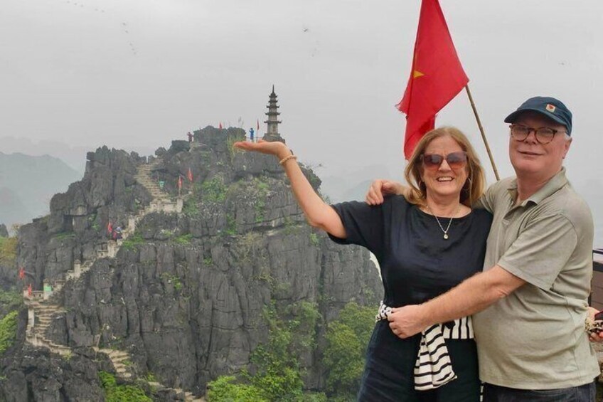 Una persona se ñala un pagodas en la cima de una montaña rocosa con una bandera. 2