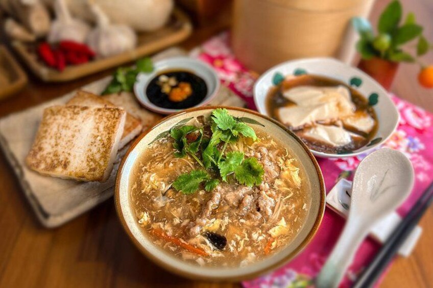 A bowl of soup with tofu and vegetables, accompanied by a bowl of broth and a plate of tofu. 1