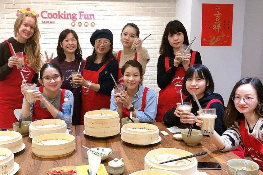 A group of people at a cooking event with cooking utensils and food containers on the table. 1