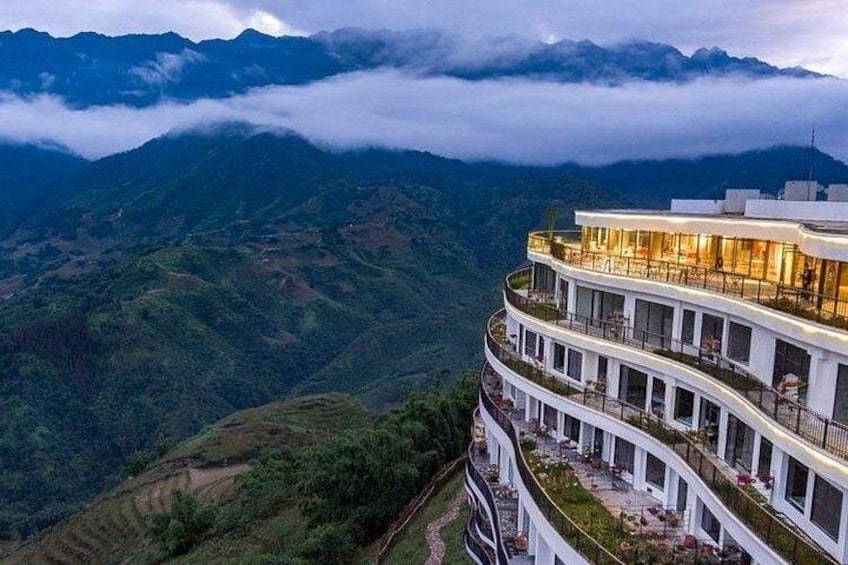 A multi-story building with balconies overlooking a mountainous landscape. 1