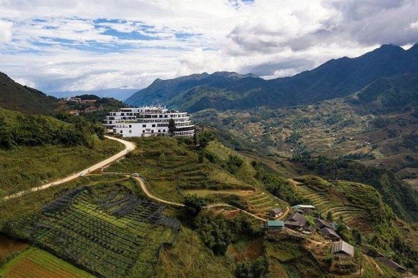 Terraced fields, a white building, and mountains in the background. 4