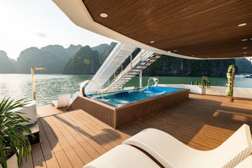 A wooden deck with a hot tub, lounge chairs, and a staircase leading to an upper deck. 3