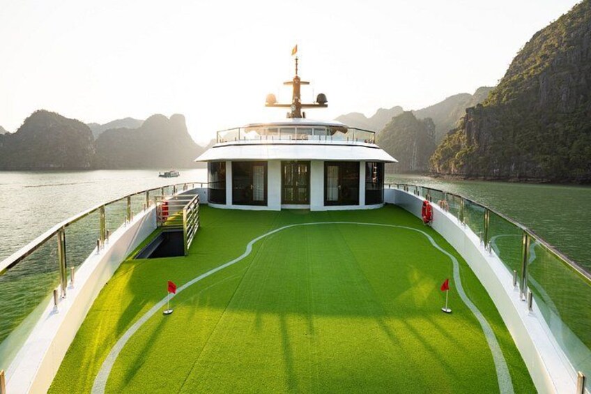 A boat with a green deck, a white superstructure, and a red flag. 5