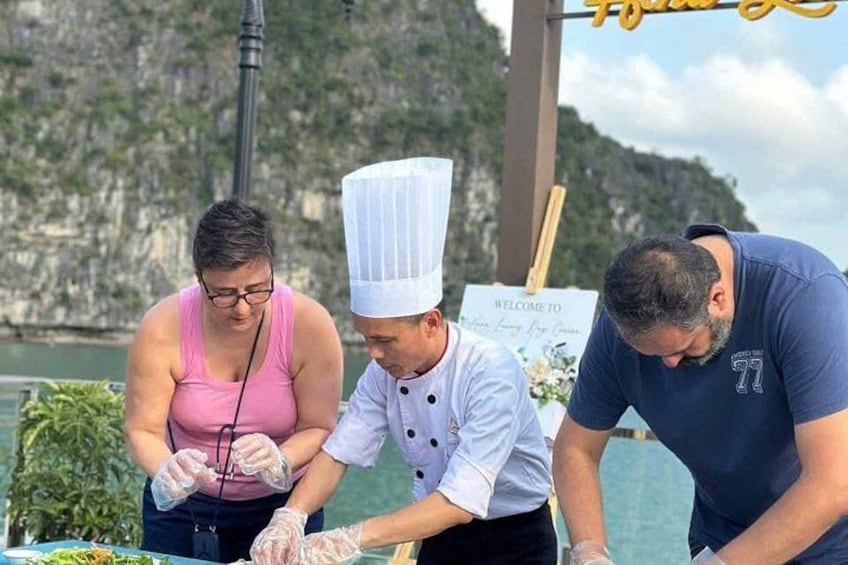 Three people preparing food outdoors with a scenic coastal background. 3