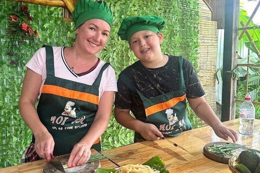 Two people wearing chef hats and aprons, chopping vegetables on a wooden cutting board. 5