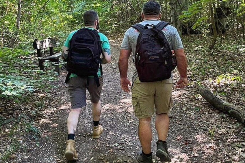 Dos personas caminando por un sendero en un bosque, cargando mochilas. 3