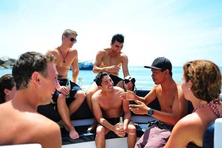 A group of people on a boat, some holding drinks, with a clear sky and water in the background. 2