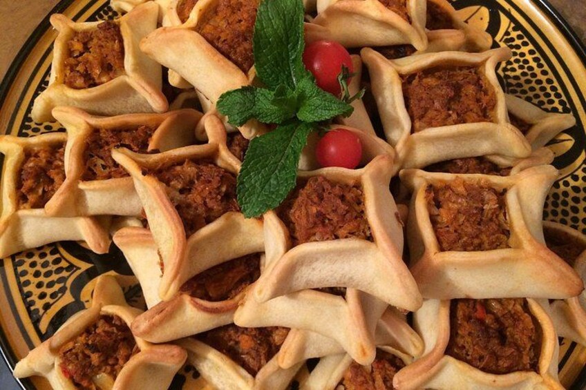 A plate of stuffed pastries with a mint leaf garnish. 3