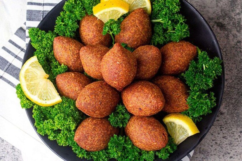 A bowl of falafel balls garnished with parsley and lemon slices. 5