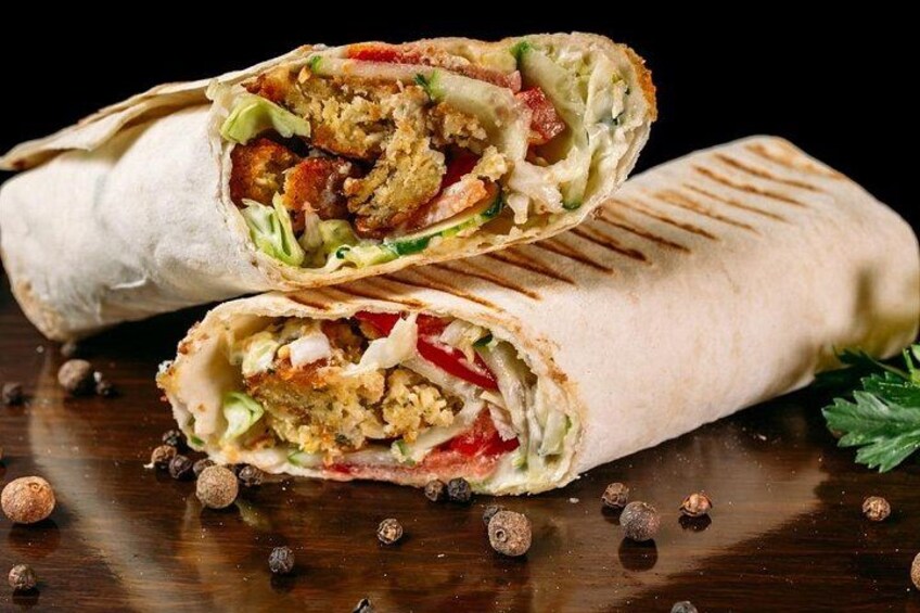 A burrito cut in half with visible fillings like lettuce, tomatoes, and possibly chicken. 2
