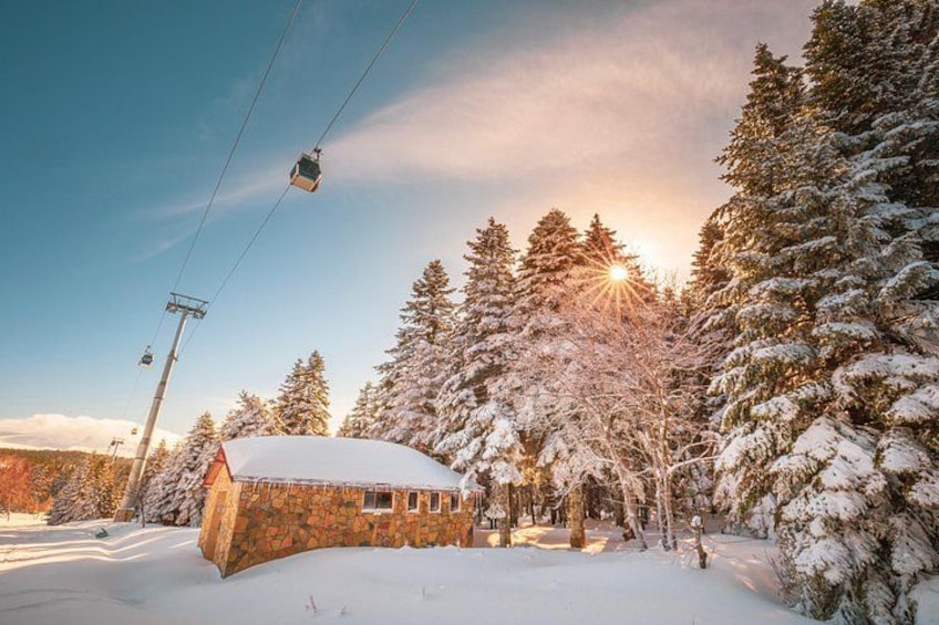 Une cabane enneigée, avec un télésiège visible au loin. 1