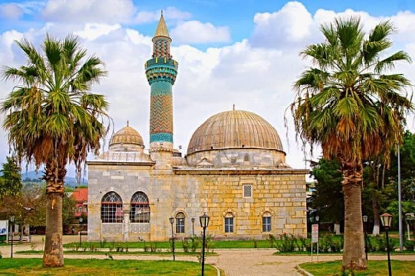 Une mosquée dotée de deux dômes et d’un minaret, entourée de palmiers et bordée d’une allée pavée. 4